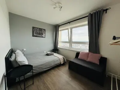 a bedroom with a bed and a chair and a window at Top Floor of the building, spectacular views! in Glasgow
