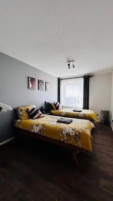 a bedroom with two beds with yellow sheets and a window at Top Floor of the building, spectacular views! in Glasgow