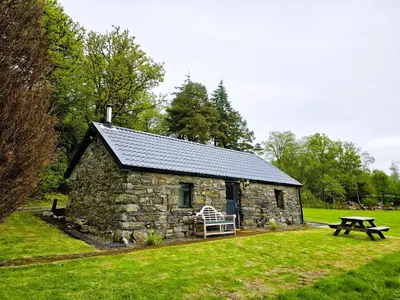 a stone house with a bench and a picnic table at Ard Veich Estate - Panoramic Highland Sea Views with private beach and woodland in Port Appin