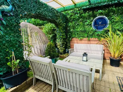a patio with a table and two chairs and a hedge at FINN VILLAGE - Loch Lomond Villa - THE JUNGLE ROOM with a PRIVATE HOT TUB in Drymen