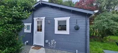 a blue shed with a white door and windows at 2 bed Lodge near Dunoon on the Shore Front in Dunoon