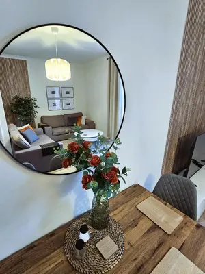 a vase of flowers on a table with a mirror at Glebe Apartment in Campbeltown