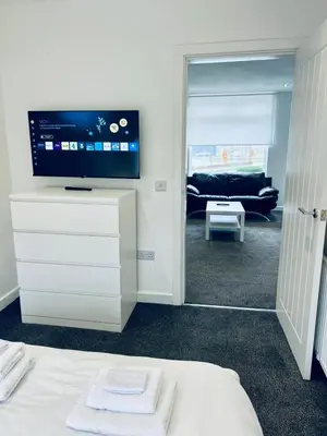 a bedroom with a tv on a dresser with a bed at Modern 2 bedroom House With Loft Conversion in Glasgow