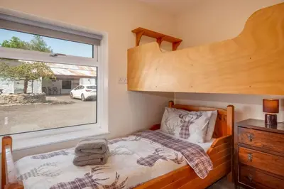 a bedroom with a bunk bed and a window at Courtyard Cottages Granary Cottage in Wigtown