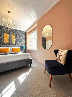 a bedroom with a bed and a chair and a mirror at St Johns Jailhouse by the Castle in Stirling