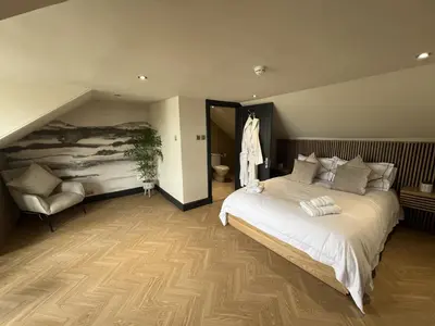a bedroom with a large white bed and a chair at 9 Bedroom all Ensuite- Exclusive Use in Auchterarder