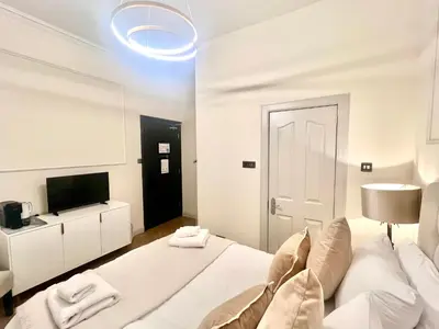 a white bedroom with a bed and a tv at 'Maisie' in ApartNest Auchterarder in Auchterarder