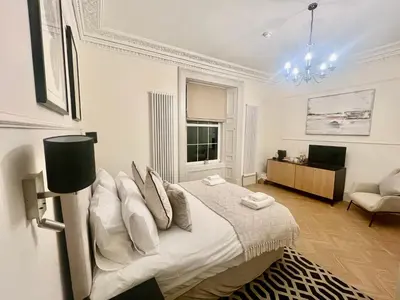 a white bedroom with a bed and a living room at 'Douglas' in ApartNest Auchterarder in Auchterarder