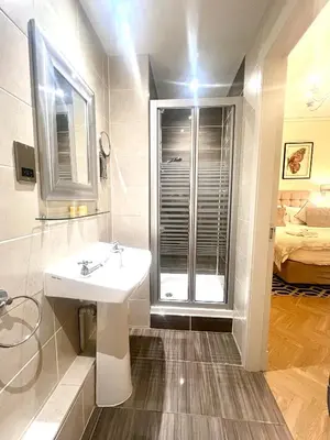 a bathroom with a sink and a shower and a bed at 'Douglas' in ApartNest Auchterarder in Auchterarder