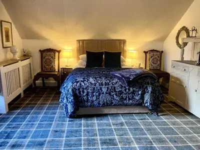 a bedroom with a bed with a blue comforter at Above & Beyond at Warriston Lodge in Moffat