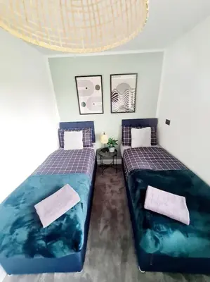 two beds in a room with blue sheets at Lovely house with back garden - PRIVATE driveway in Glasgow