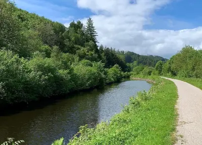 a river with a path next to a road at Rowan Log Cabin in Dalavich