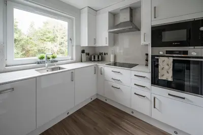a white kitchen with white cabinets and a window at Quiet 2 bedroom gem in Stirling in Bridge of Allan