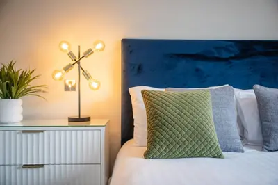 a bedroom with a bed with a green pillow and a nightstand at Quiet 2 bedroom gem in Stirling in Bridge of Allan