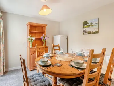a dining room with a wooden table and chairs at Carraig-Dhubh South - Uk47124 in Whiting Bay