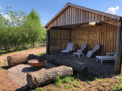 a wooden gazebo with chairs and a fire pit at The Bothy and Wagon at Pitmeadow Farm in Perth