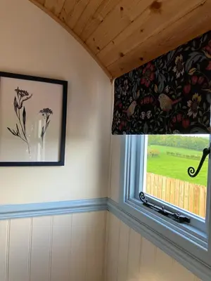 a window in a room with a curtain with flowers at Wee Shepherds Hut Maybole in Maybole