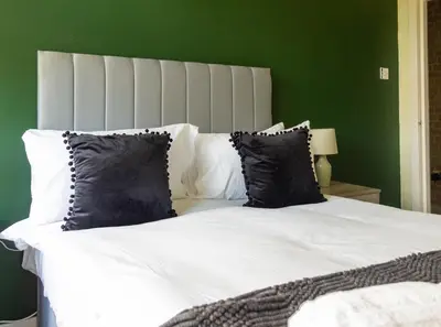 a bedroom with a white bed with black pillows at 1 BDR Apt At Caledonia Luxe Stays Short Lets & Serviced Accommodation Paisley in Paisley