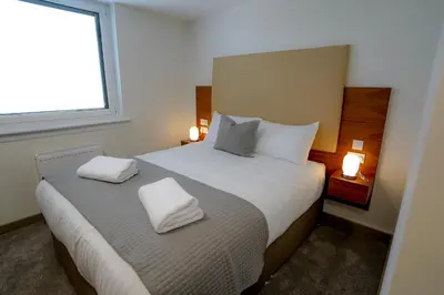 a bedroom with a bed with two white towels on it at Hardgate House Hotel in Clydebank