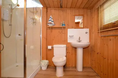 a bathroom with a toilet and a sink and a shower at Seil Log Cabin in Dalavich