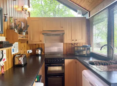 a kitchen with wooden cabinets and a stove top oven at Seil Log Cabin in Dalavich