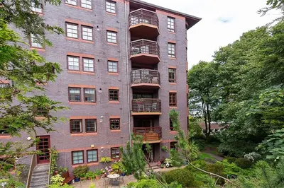 a tall brick building with balconies and trees at Orchard Brae in Edinburgh