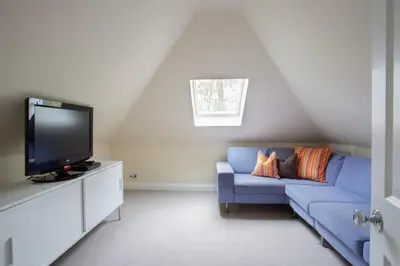 a living room with a blue couch and a tv at Large and luxurious country home near Glasgow in Eaglesham