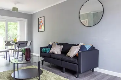 a living room with a black couch and a mirror at Croftspar House in Glasgow