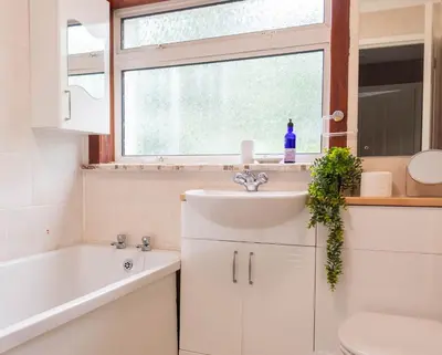 a bathroom with a sink and a toilet and a window at Croftspar House in Glasgow