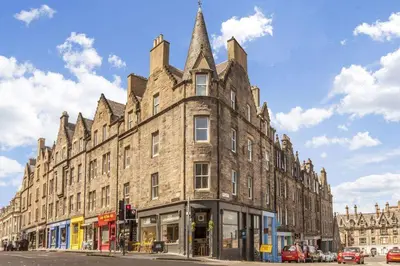 a large brick building with a pointed roof on a street at Spacious boutique two-bedroom apartment next to the castle in Edinburgh