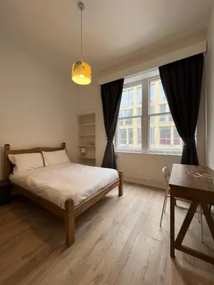 a bedroom with a bed and a large window at Spacious boutique two-bedroom apartment next to the castle in Edinburgh