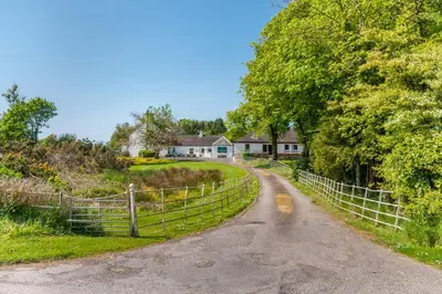 a dirt road with a fence next to a house at Courtyard Cottages Rose Cottage in Wigtown
