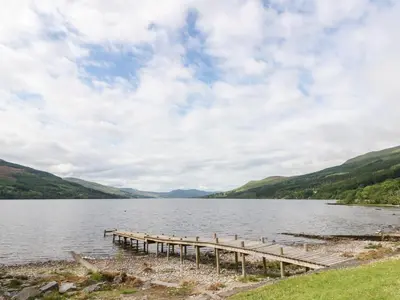 a dock on a lake with hills in the background at Kalipé in Aberfeldy