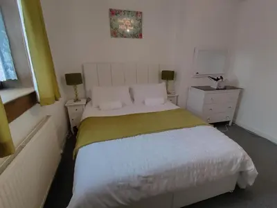 a bedroom with a white bed with a yellow blanket at Kumba in Kilmarnock
