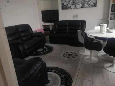 a living room with black leather furniture and a table at Kumba in Kilmarnock