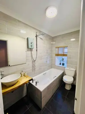 a bathroom with a tub and a toilet and a sink at Beautiful spacious apartment in town centre in Oban
