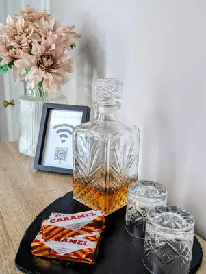 a bottle of whiskey on a table with some snacks at Beautiful spacious apartment in town centre in Oban