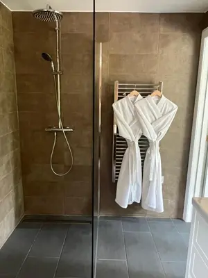 a bathroom with a shower with white towels on a rack at Aos Sí - Wellness - Jacuzzi - Lodges in Ballachulish