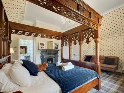 a bedroom with a canopy bed and a fireplace at St John's Old Rectory in Glencoe