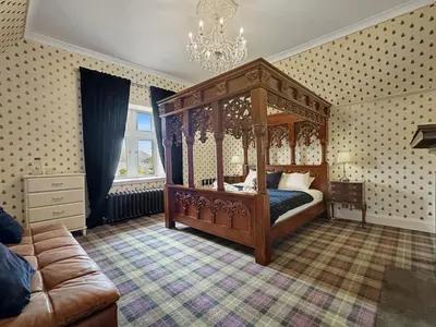 a bedroom with a canopy bed and a couch at St John's Old Rectory in Glencoe