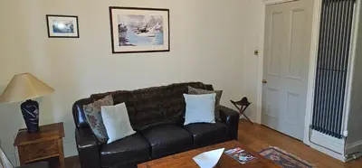 a living room with a leather couch and a table at Snug - Macushla Apartment in Helensburgh