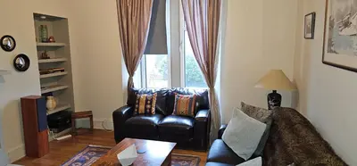 a living room with a leather chair and a window at Snug - Macushla Apartment in Helensburgh
