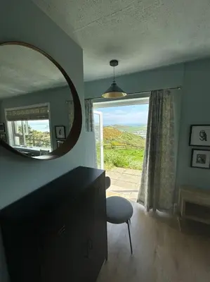 a room with a mirror and a chair and a window at Stunning Rathlin cottage in Rathlin Island