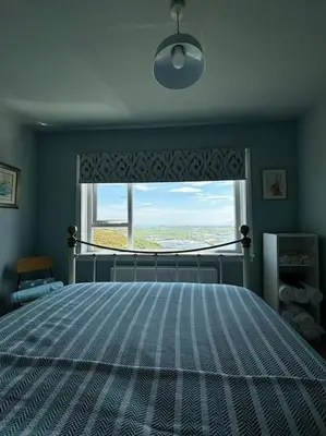 a bedroom with a large bed and a window at Stunning Rathlin cottage in Rathlin Island