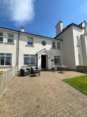 a large white house with a patio in front of it at Beachside House Rathlin Island in Rathlin Island