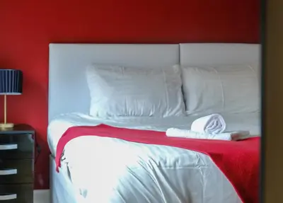 a bedroom with a white bed with a red wall at Register House Family or Contractor 4bed with Garden Driveway in Bellshill