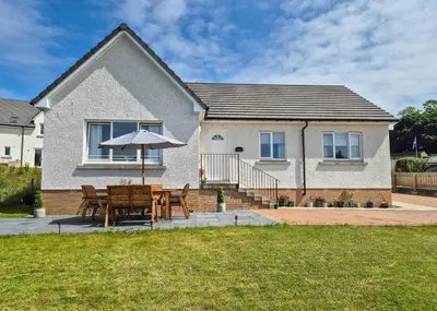 a table and an umbrella in front of a house at Kilin in Lochgilphead