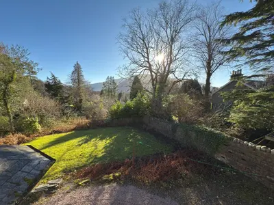 a grassy yard with the sun in the background at Highland Hideaway in Fort William