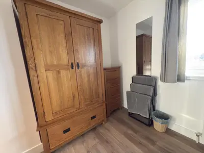 a bedroom with a large wooden cabinet and a chair at Highland Hideaway in Fort William