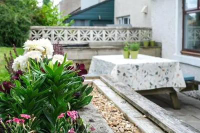 a patio with a table and flowers and a bench at Lang Toon House - 3 bedrooms in Auchterarder
